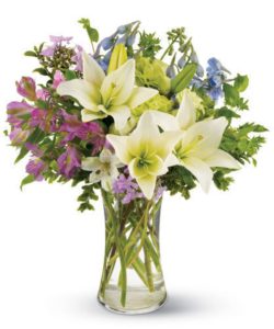  a heavenly breeze drifts by, carrying the fragrance of garden flowers. White lilies, lofty blue delphinium and purple and green blossoms mingle together to create this casual bouquet, just right for any occasion.