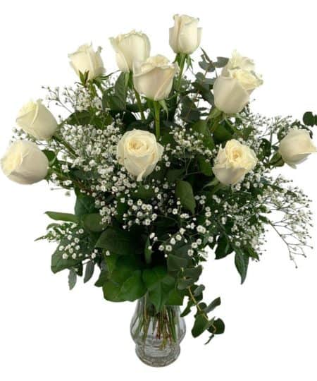 Our designers create this wonderful arrangement of twelve white roses with shimmering accents in a glass vase for sparkling splendor. Vase may vary. Approximately 26"H x 20"W.