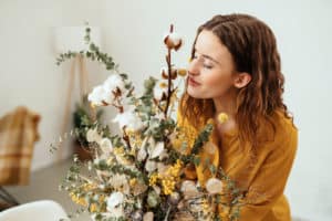 Blissful young woman smelling a flower arrangement at home with her eyes closed in appreciation in a close up side portrait